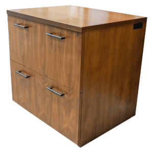 Used JSI 30"W Walnut Two-Drawer Lateral File W/ Grommet's  This two-drawer lateral file offers a sleek walnut finish and spacious filing capacity, ideal for storing important documents in commercial settings. Grommets located on left and right side. Two Back Pull Handles Per Drawer  Locking Grommets Dimensions: 30"W x 26" D x 30"H Ideal for offices, executive suites, and collaborative workspaces.